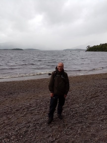 Gary pictured on a pebbled beach with the sea behind him on a cloudy day