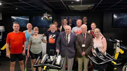 A group shot of all those who took part in the challenge stood behind two spin bikes