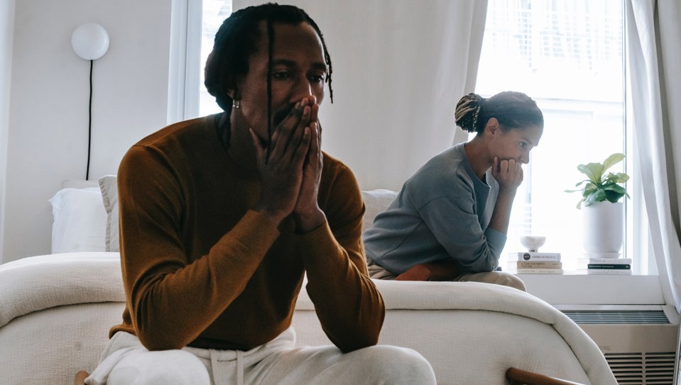 A photo of an unhappy couple sitting on bed after having argument