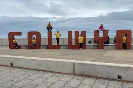 Members of blind veteran Griff's family, each posing on the giant concrete letter which spell out "Colwyn"