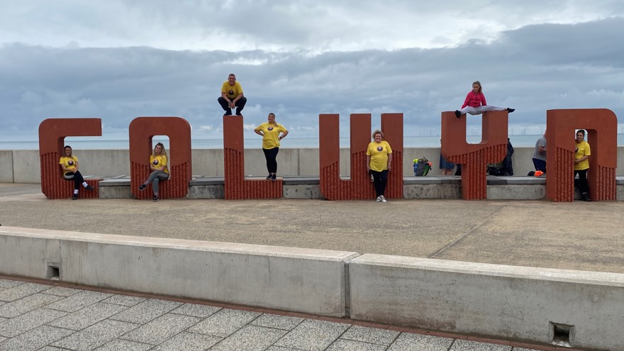 Members of blind veteran Griff's family, each posing on the giant concrete letter which spell out "Colwyn"