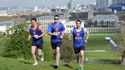 A photo of blind veteran Rob running up a hill with two friends wearing Blind Veterans UK running tops