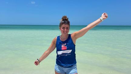 Evie standing in front of the sea with her Blind Veterans UK t-shirt