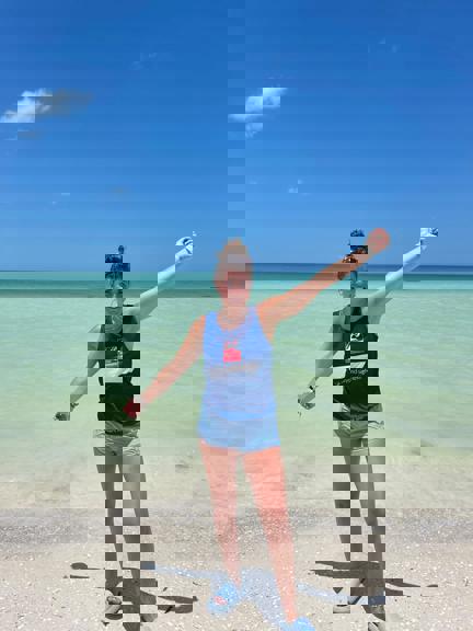 Evie standing in front of the sea with her Blind Veterans UK t-shirt