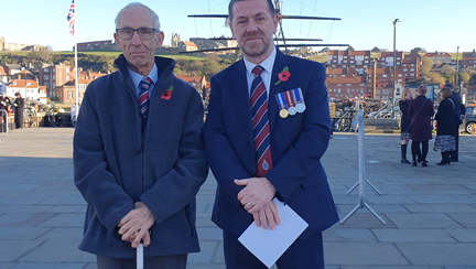 Blind veterans Alan and Andy at Whitby Remembrance service standing in front of a ship
