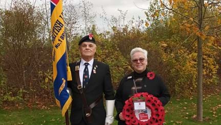 A photo of community support worker Anne (right) with blind veteran and standard bearer Wayne at the funeral of Geoffrey John Barker