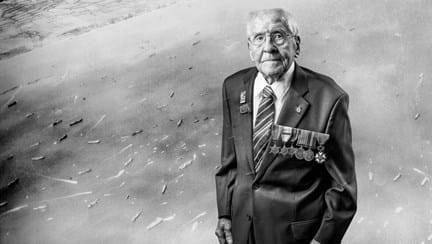 A black and white portrait of blind veteran Thomas, overlaid on a scene from D-Day