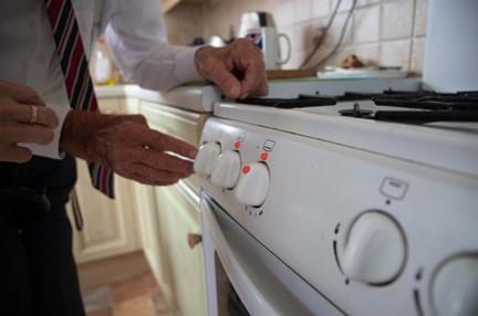 Photo of Eddie using an oven with bumpons, a round adhesive dot used to mark every day items around the house