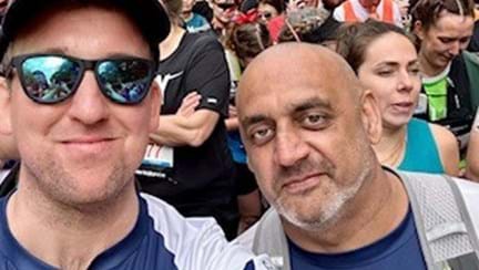 Naz and Richard taking a selfie at the London Marathon with huge crowds of runners behind them