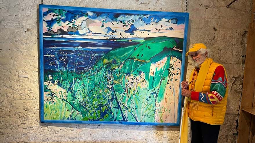 Blind veteran Philip stands with a white cane on the right hand side of his artwork