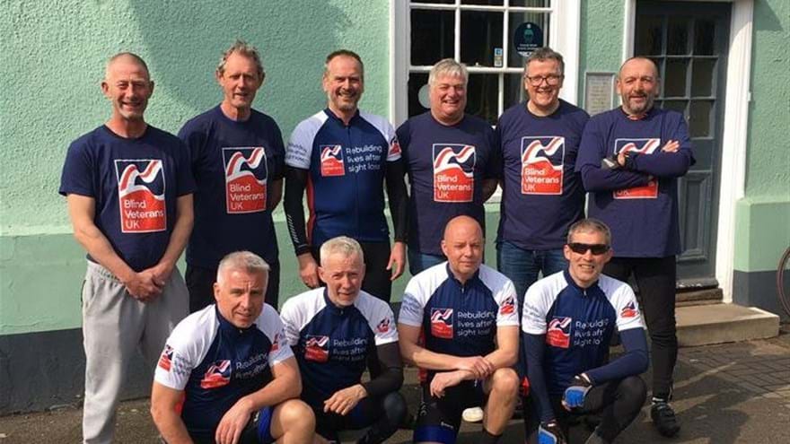 A group picture of ten men who make up the cyclists for the 400 mile bike ride and their support crew all wearing Blind Veterans UK tops