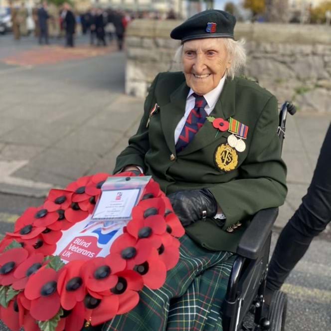 Photo of blind veteran Margaret pictured holding a poppy wreath at Remebrance Sunday