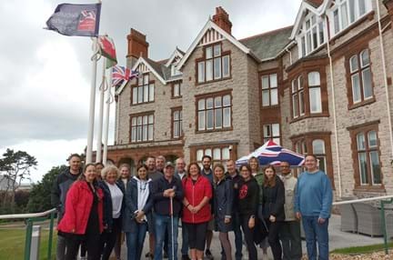 Group shot of Thea Pharmaceuticals team members with blind veteran Billy and Wellbeing Specialist Karla out side Blind Veterans UK's Llandudno Centre of Wellbeing