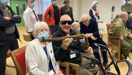 Photo of blind veteran Barry, right, and wife Joan, left, holding a gun during demonstration