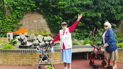 Blind veteran Nancy raises her arm in celebration of completing 100th lap