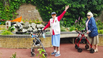 Blind veteran Nancy raises her arm in celebration of completing 100th lap