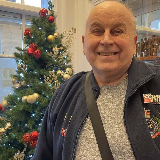 Blind veteran Wally standing in front of a Christmas tree at our Llandudno centre