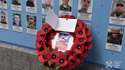A Blind Veterans UK wreath and a written card, pictured laying next to portraits of Ukrainian solders