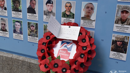 A Blind Veterans UK wreath and a written card, pictured laying next to portraits of Ukrainian solders