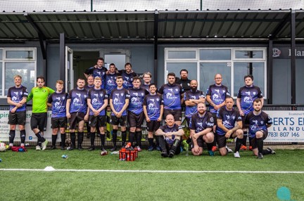 Group photograph of the team wearing their football kit of blue t-shirts and black shorts