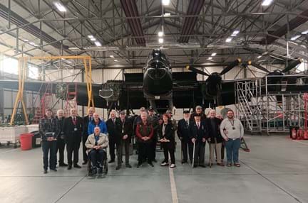A group of Members, staff, and volunteers standing in front of a plane at RAF Conningsby