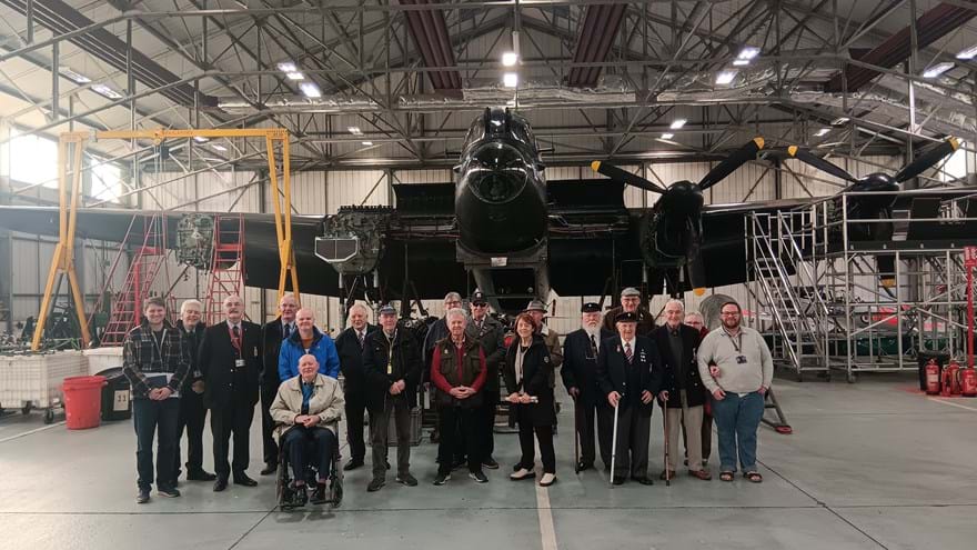 A group of Members, staff, and volunteers standing in front of a plane at RAF Conningsby