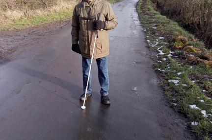 Blind veteran Brian walking along a path with a white cane