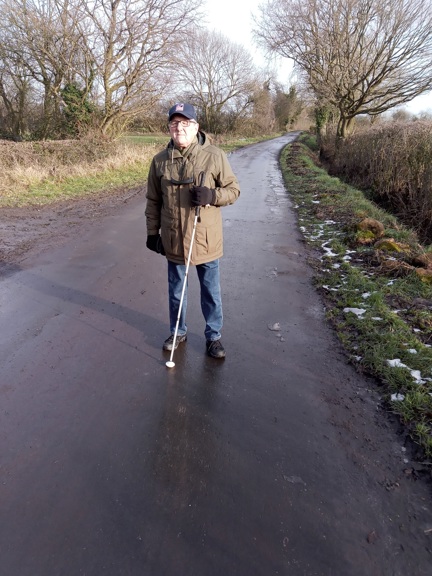 Blind veteran Brian walking along a path with a white cane