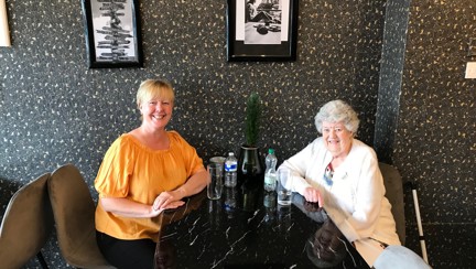 Chrissie and Lorna sat at a table in a restaurant, they are both smiling