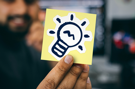 A man holding a sticky note with a light bulb icon on it