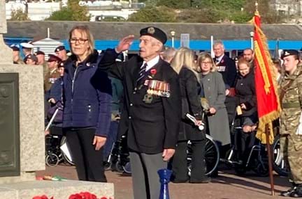 Blind veteran Victor, wearing his medals and uniform, salutes after laying a poppy wreath