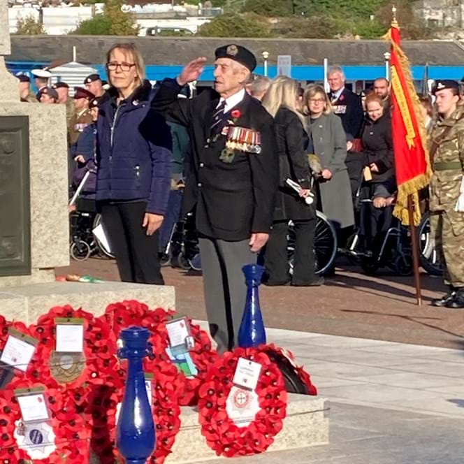 Blind veteran Victor, wearing his medals and uniform, salutes after laying a poppy wreath