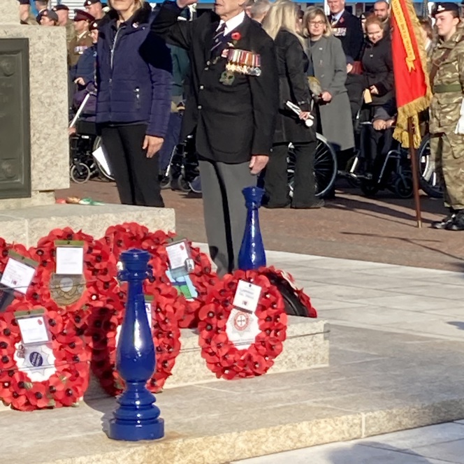 Blind veteran Victor, wearing his medals and uniform, salutes after laying a poppy wreath