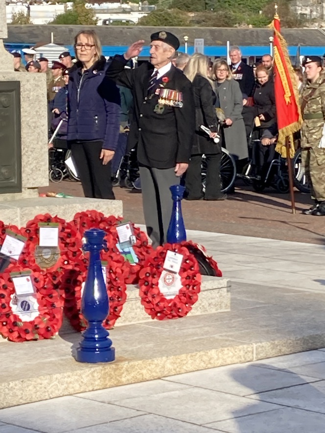 Blind veteran Victor, wearing his medals and uniform, salutes after laying a poppy wreath