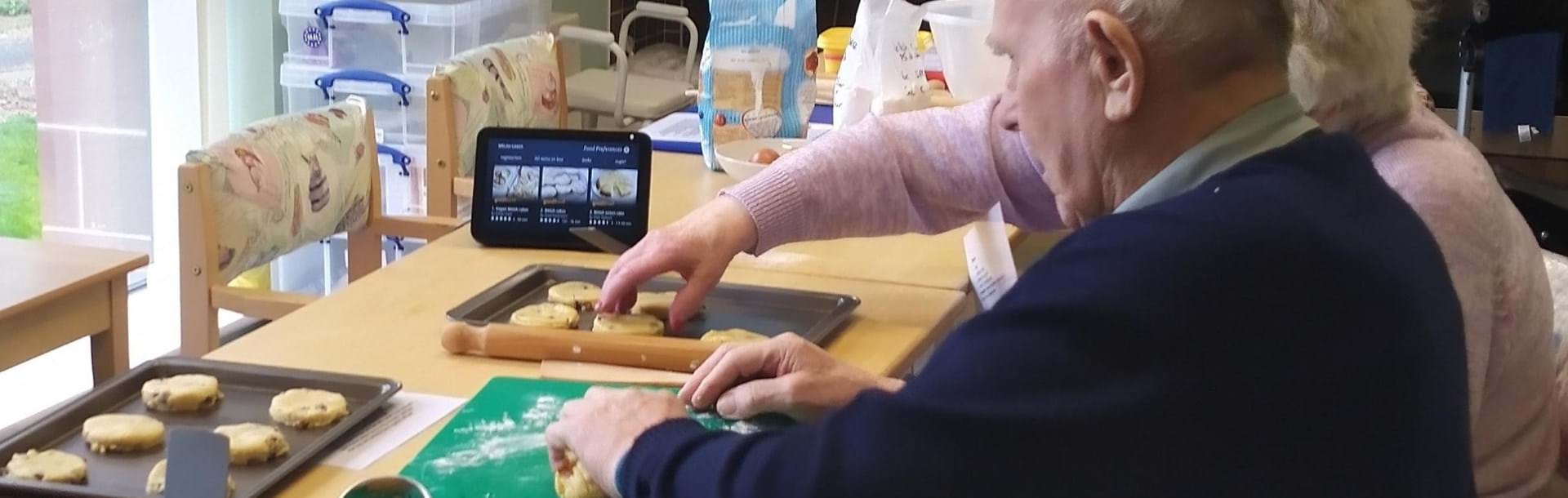 A photo of blind veteran Ian and his wife Mabel rolling out dough for Welsh cakes with the help of Alexa