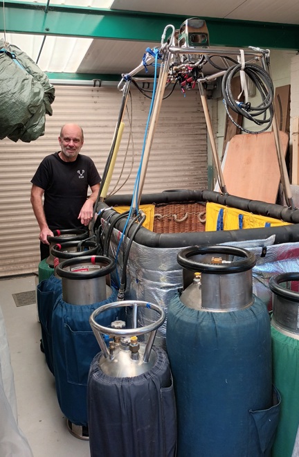 Blind veteran Mike stands next to the hot air balloon basket and gas canisters that will fuel his flight