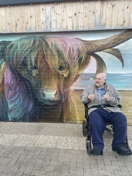 Blind veteran Maurice is in his wheelchair next to a large mural of a buffalo