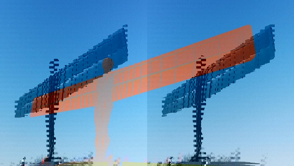 The Angel of the North statue, a large steel sculpture with wide spanning wings, placed on a grassy hill.