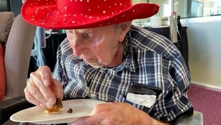Blind veteran Ken wearing a red hat and eating Christmas cake