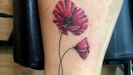 A close up of a tattoo of two red poppies