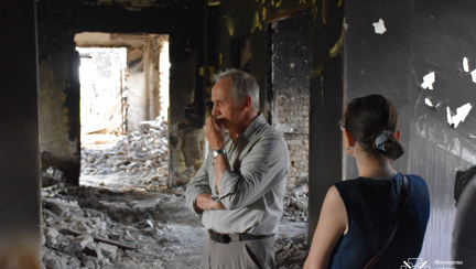 Nick Caplin is pictured with his hand to his mouth, looking pensive as he stands in a destroyed building in Ukraine