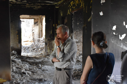 Nick Caplin is pictured with his hand to his mouth, looking pensive as he stands in a destroyed building in Ukraine