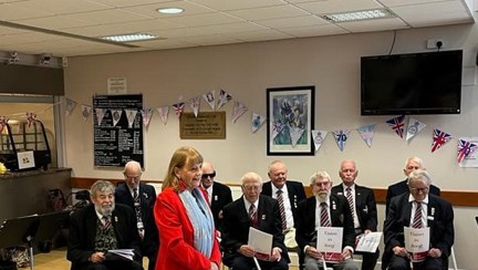 Jennie stands in the foreground in formal attire, with the choir sitting down behind her, also in formal attire, ready to perform