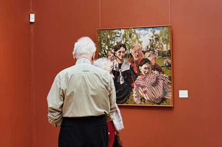 An elderly man looking at painting