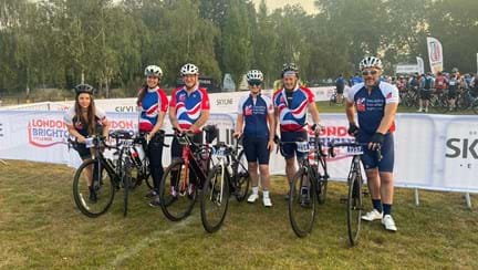 A group of six Thea employees holding up their bikes and wearing their Blind Veterans UK cycling tops