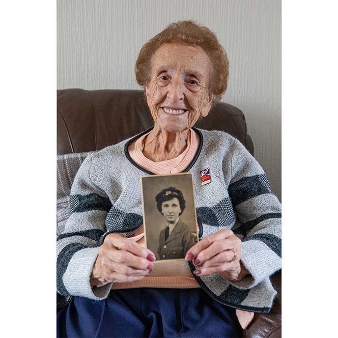 Margaret sat down smiling and holding a black and white picture of herself from when she served.