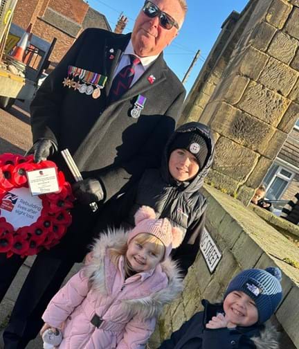 Colin and his three of his grandchildren with a wreath of poppies