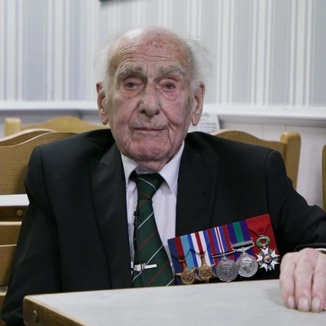 A photo of Blind veteran Harry sitting at a table during an interview
