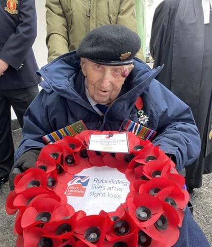 Ken in his beret and holding a poppy wreath 