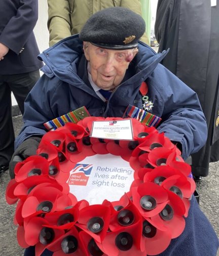 Ken in his beret and holding a poppy wreath 